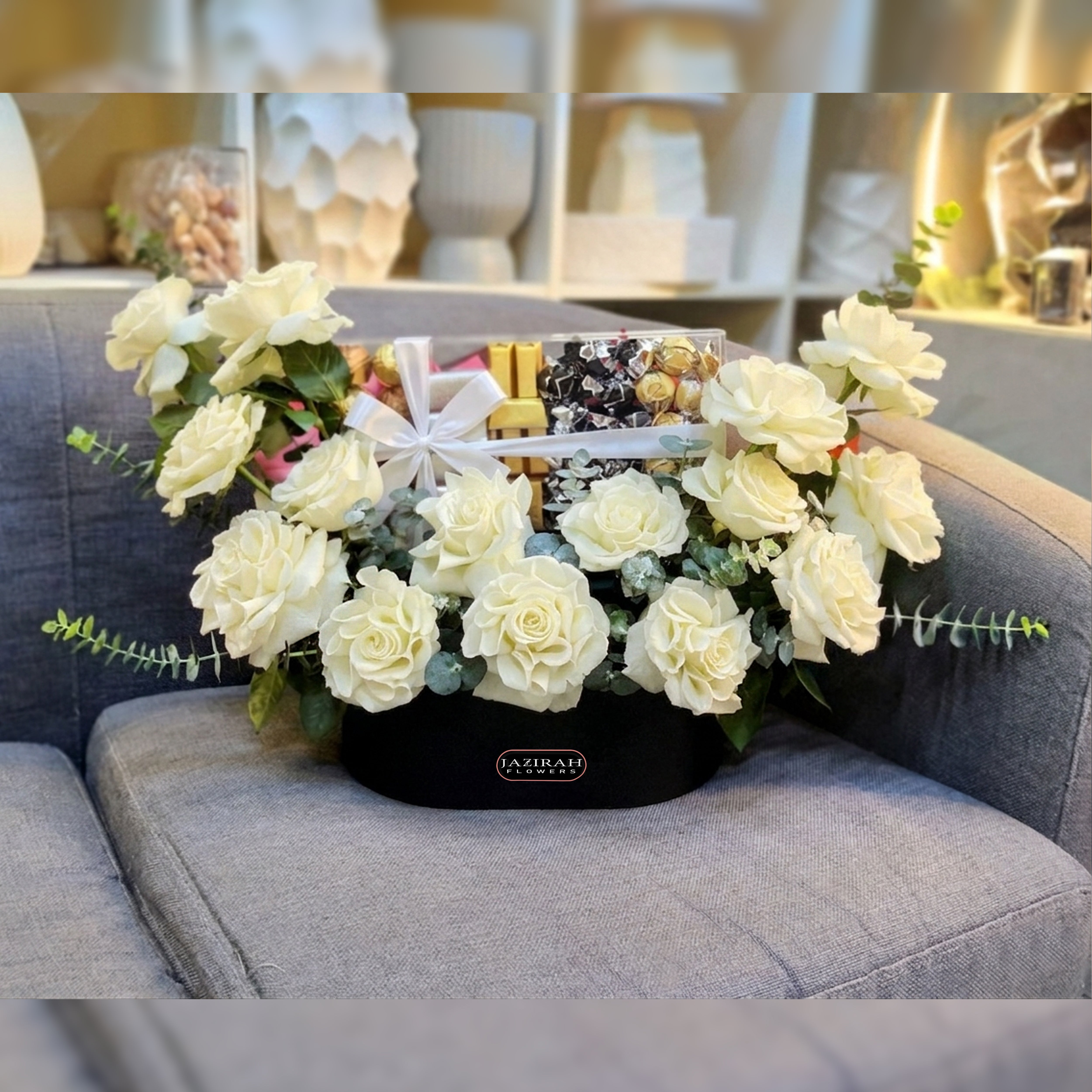 Premium white roses bouquet with assorted luxury chocolates in a black leather box by Jazirah Flowers UAE.